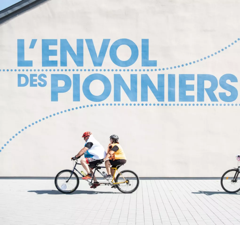 Des participants au Vélotour Occitanie à vélo devant l'enseigne de L'Envol des Pionniers