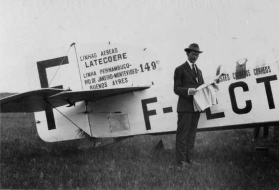 Homme lisant un journal devant un avion au Brésil, au temps de l'Aéropostale